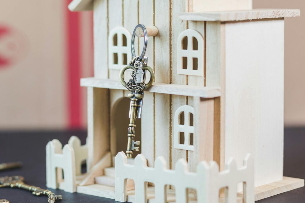 Miniature wooden house with a vintage key, symbolizing real estate and homeownership.